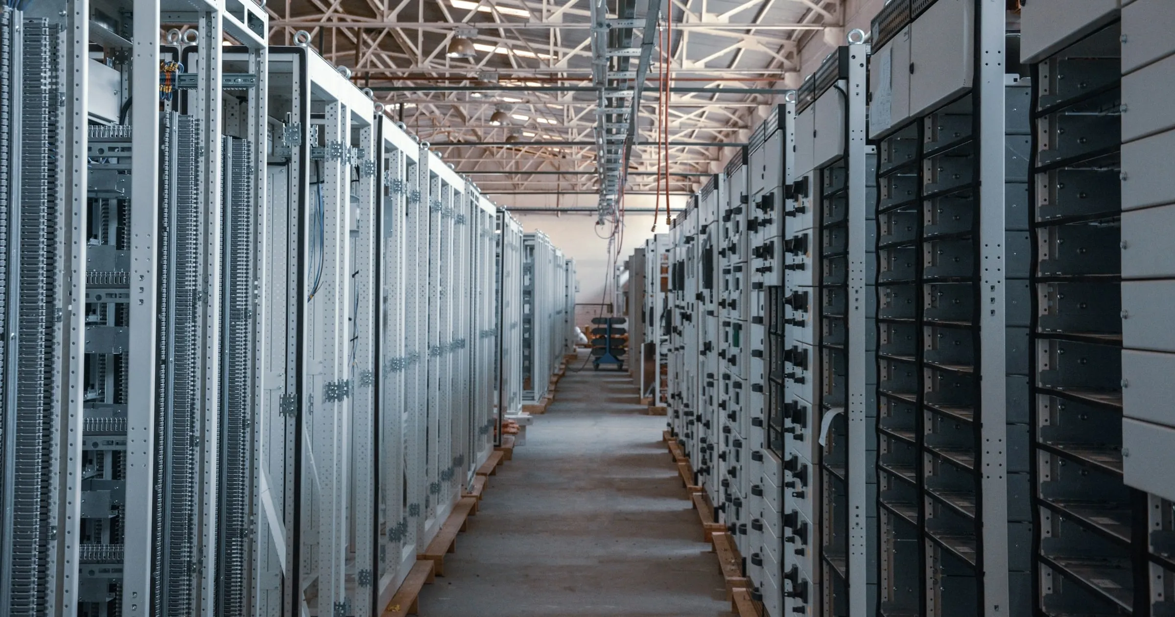 A corridor between two long rows of identical equipment cabinets.