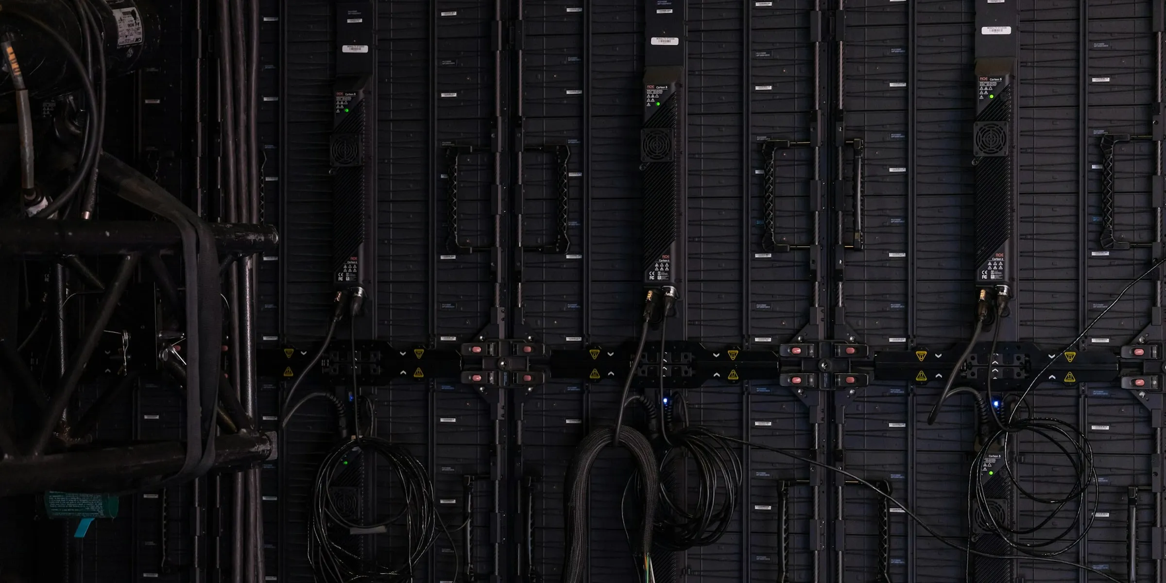 Rack-mounted equipment in near-darkness, cabling coiled and dressed to the frame.